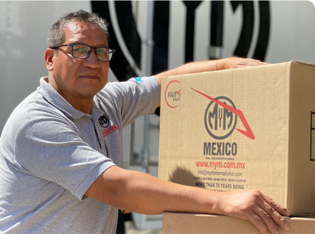 Operador logistico de mudanza transportando caja de carton con el logo de MyM by Traxión