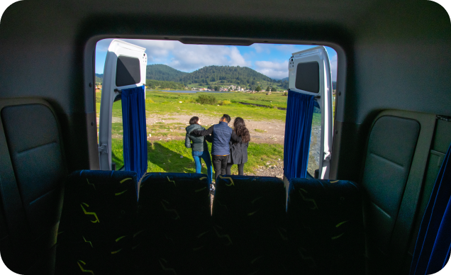 Van vista de adentro hacia afuera llegando de un viaje, afuera se ven 3 turistas.