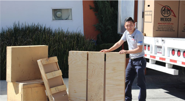 Operador de MyM by Traxión con estibas de madera junto a camión de mudanzas